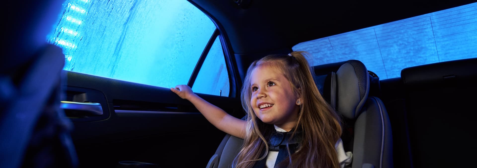 Car going through a brightly lit car wash tunnel with water and soap